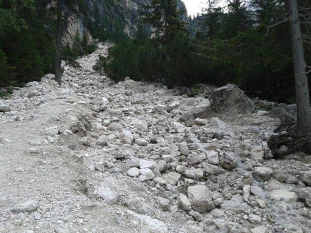 Lago di Braies Sentiero di sassi che sale verso l'alto tra alberi