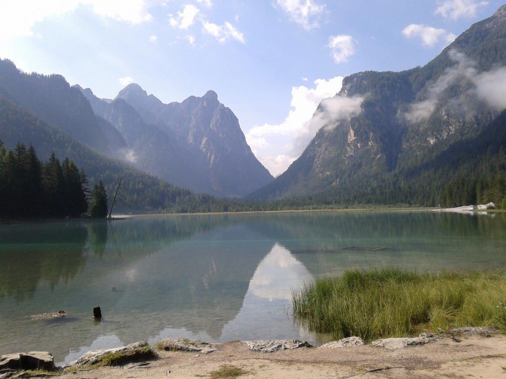 Lago di Dobbiaco con montagne su sfondo e pezzo di costa