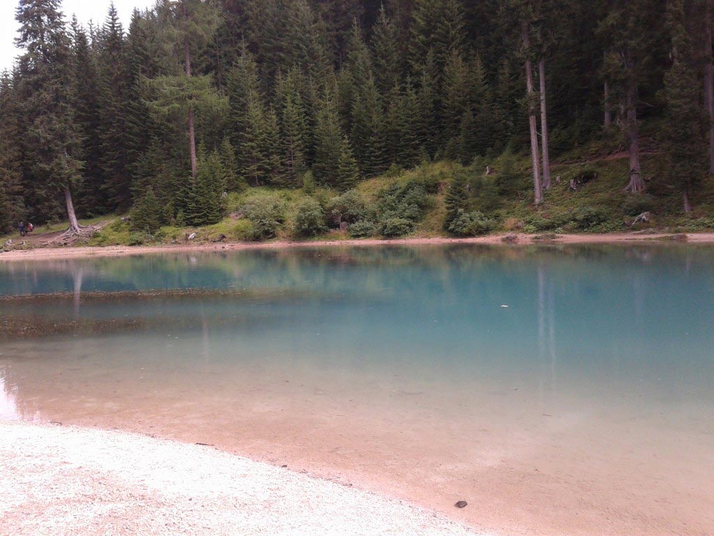 Acque rosa e azzurre del Lago di Misurina con alberi su sfondo